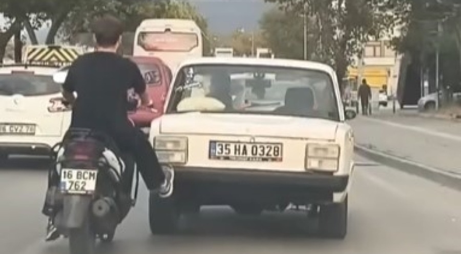 Bursa'da motosikletli genç, yolda kalan aracı tek ayağıyla itti