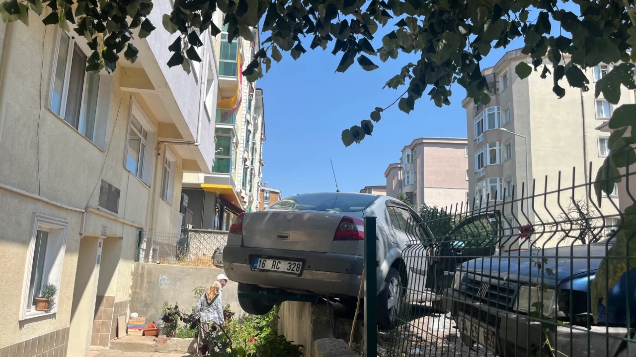 El frenini çekmeyi unuttu, araç bahçe duvarında asılı kaldı