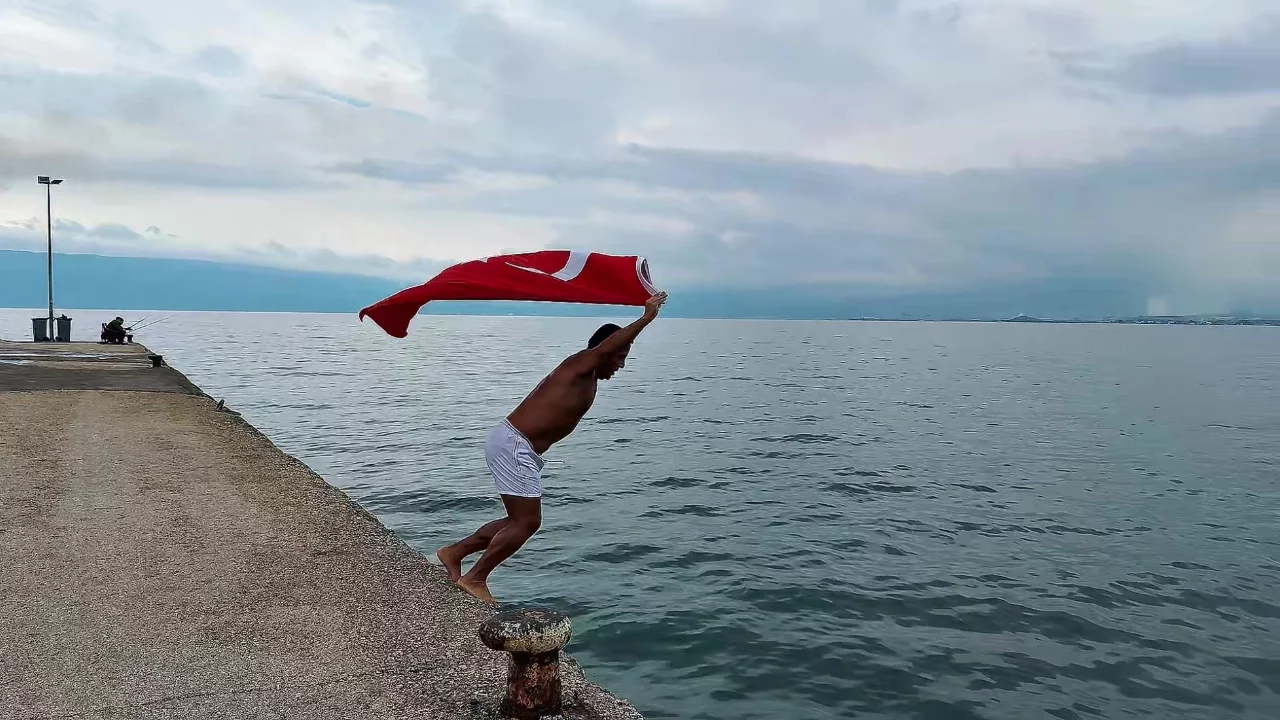 Bursa'da soğuk ve yağışlı havaya aldırmadı, Türk bayrağıyla denize girdi
